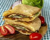 Pyszne panini z kurczakiem, suszonymi pomidorami i serem, podane z pomidorkami koktajlowymi i sałatą.