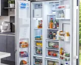 Offener Kühlschrank mit Lebensmitteln, darunter gefrorene Produkte und Getränke. Die Temperatur im Gefrierschrank ist ideal für die Lagerung.