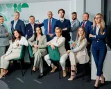 Zespół prawników w garniturach pozuje do zdjęcia w nowoczesnym biurze.