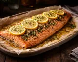En hel, lyxig lax i ugn, toppad med citronskivor och örter, serverad på ett fat med bakplåtspapper.