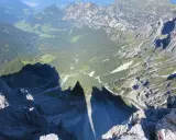 Ombra delle **Torri del Vajolet** che si allunga su un paesaggio alpino di boschi e valli verdi.