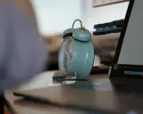 Budzik obok laptopa i klawiatury. Czas na pracę na 3/4 etatu.