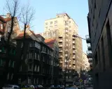 Wysoki, jasny drapacz chmur w Katowicach góruje nad starą kamienicą.