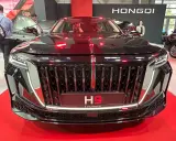 Elegancki czarny Hongqi H9 z chromowanym grillem i czerwonymi akcentami. Zainteresowani sprawdzają jego cenę na wystawie.