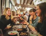 Amies joyeuses partageant des tapas dans un resto ouvert le dimanche à Rennes. Ambiance chaleureuse et conviviale.