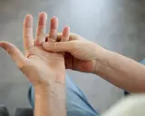 Eine Hand massiert die andere, um **Schmerzen in der Hand** zu lindern.