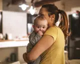 Zmęczona mama tuli dziecko, szukając sposobu, jak oduczyć dziecko jeść w nocy.