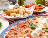 Un assaggio di cosa mangiare in Campania: gnocchi fritti, bruschette e un piatto di pasta al pomodoro e mozzarella.