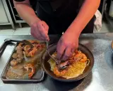 Un chef prépare des pâtes aux crevettes et pétoncles, un plat savoureux de cuisine de terroir.