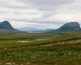 Vast, green valley with mountains and lakes, perfect for hiking trails Sweden.