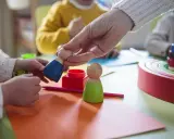Dzieci bawią się drewnianymi ludzikami. W żłobku od jakiego wieku można zapisać dziecko?