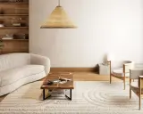 En modern lounge med en böjd soffa, träbord och två fåtöljer. Mattan med cirkelmönster ser ut att behöva fixa nedtrampad matta för att återfå sin form.