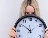 Dziewczyna z blond włosami ukrywa się za zegarem, patrząc zza niego. Czyżby czas miał dla niej jakieś szczególne 2233 znaczenie?