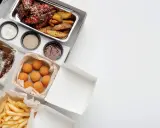 Variedad de comida para llevar: alitas, costillas, papas fritas, croquetas y pan. ¡Todo listo para disfrutar!