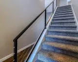 Miękka wykładzina na schody betonowe zapewnia komfort i bezpieczeństwo. Nowoczesna balustrada z linkami dodaje elegancji.