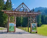 Ingresso in legno per il regno del gigante Baranci, con cartelli informativi e sentiero che si addentra nel bosco.