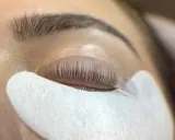 Un œil fermé, les cils recourbés sur un pad, prêts pour un allongement.