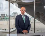 Mann im Anzug blickt nachdenklich, während im Hintergrund das Reichstagsgebäude zu sehen ist. Er spricht über die **Herausforderungen des Sozialstaats**.