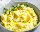 Miseczka kremowego puree ziemniaczanego z masłem, ziołami i pieprzem.
