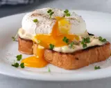 Un delicioso huevo poche con yema líquida cayendo sobre tostadas, adornado con brotes verdes y pimienta.