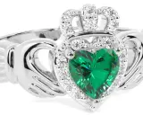 Anello Claddagh con cuore verde smeraldo, circondato da diamanti e sormontato da una corona scintillante.