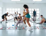 Gruppe trainiert mit Seilen und Leitern. Ein Mann gibt Anweisungen, während andere intensives Intervalltraining absolvieren.