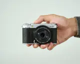 Mano sujetando una cámara Fujifilm X-M5 plateada y negra, lista para capturar momentos.