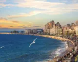 Il porto di Alessandria d'Egitto, con la sua vivace Corniche al tramonto, le onde del Mediterraneo e i gabbiani in volo.