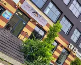 Elegancki budynek z oknami i drzwiami, z zielenią przed wejściem.