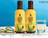 Dwa butelki napoju Forever Aloe Vera Gel, z widocznymi plastrami aloesu i szklanką napoju. Odkryj aloes właściwości.