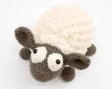 Oveja amigurumi de ganchillo con lana crema y marrón, ojos grandes y expresivos, lista para abrazar.
