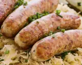Aksamitna biała kiełbasa w kiszonej kapuście, posypana szczypiorkiem. Pyszne danie gotowe do podania.