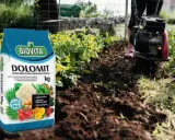 Torba z nawozem Dolomit Biovita obok grządki, gdzie glebogryzarka spulchnia ziemię. Czy dolomit jest szkodliwy? Nie, jest to wapno nawozowe z magnezem.