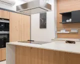 Nowoczesna kuchnia z wyspą, płytą indukcyjną i okapem. Na ścianie wisi zegar.