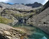 Riflessi perfetti sul lago nero, incastonato tra montagne rocciose e verdi pendii.