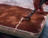 Kto pyta, czy mascarpone jest fit, gdy widzi tak kuszące tiramisu? Nóż kroi deser, odsłaniając kremową warstwę.