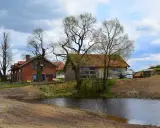 Idealne miejsce gdzie na weekend we dwoje: urokliwe domki z cegły i drewna nad stawem, otoczone drzewami.