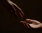 Due mani si sfiorano, un gesto che racchiude il significato di connessione, speranza e un nuovo inizio.