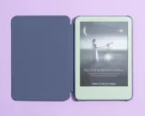 Granatowe etui na Kindle 11 obok zielonego czytnika. Na ekranie Kindle grafika z kobietą i teleskopem.
