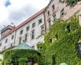 Zamek w Otmuchowie, porośnięty bluszczem, z polską flagą na wieży. Wspaniałe otmuchowskie atrakcje czekają na odkrycie!