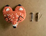 Un adorable zorro naranja tejido a crochet, listo para convertirse en un broche. ¡Perfecto para quienes buscan patrones de broches crochet únicos!
