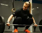Eine Frau in Sportkleidung bereitet sich auf das Gewichtheben vor. Eine **1 Woche Trainingspause sinnvoll** für Regeneration und neue Kraft.
