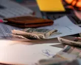 Pieniądze na dokumentach, portfel i klawiatura. Symbolizują wsparcie finansowe, np. refundację pieluchomajtek dla osób ze znacznym stopniem niepełnosprawności.