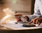 Manos calculando gastos y revisando recibos. Planificar el futuro financiero, como un plan de pensiones, merece la pena.