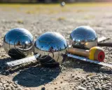 Trois boules de pétanque brillantes, un cochonnet et un mètre sur un terrain de gravier. Le jeu du joueur de boules est prêt.