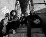 Tre uomini con cappuccio siedono sulle scale, un'atmosfera da musica hip hop famosa.