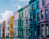 Kolorowe kamienice w Notting Hill w Londynie, tworzące tęczowy rząd pod błękitnym niebem.