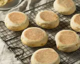 Plusieurs muffins anglais dorés et moelleux refroidissent sur une grille. Parfaits pour le petit-déjeuner.