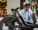 Un homme en casque retire la batterie de son vélo électrique, prêt pour l'immatriculation vélo électrique.