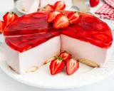 Pyszny sernik na zimno z mascarpone, udekorowany galaretką i świeżymi truskawkami. Idealny na letnie popołudnie.
